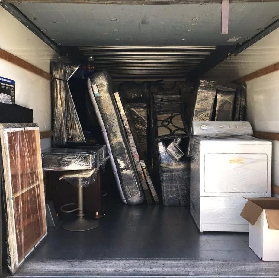 Moving truck interior packed with wrapped furniture and appliances