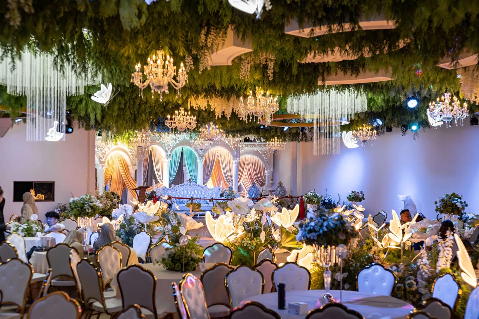 Luxurious wedding venue with hanging garden installations, chandeliers, and decorated tables ready for reception