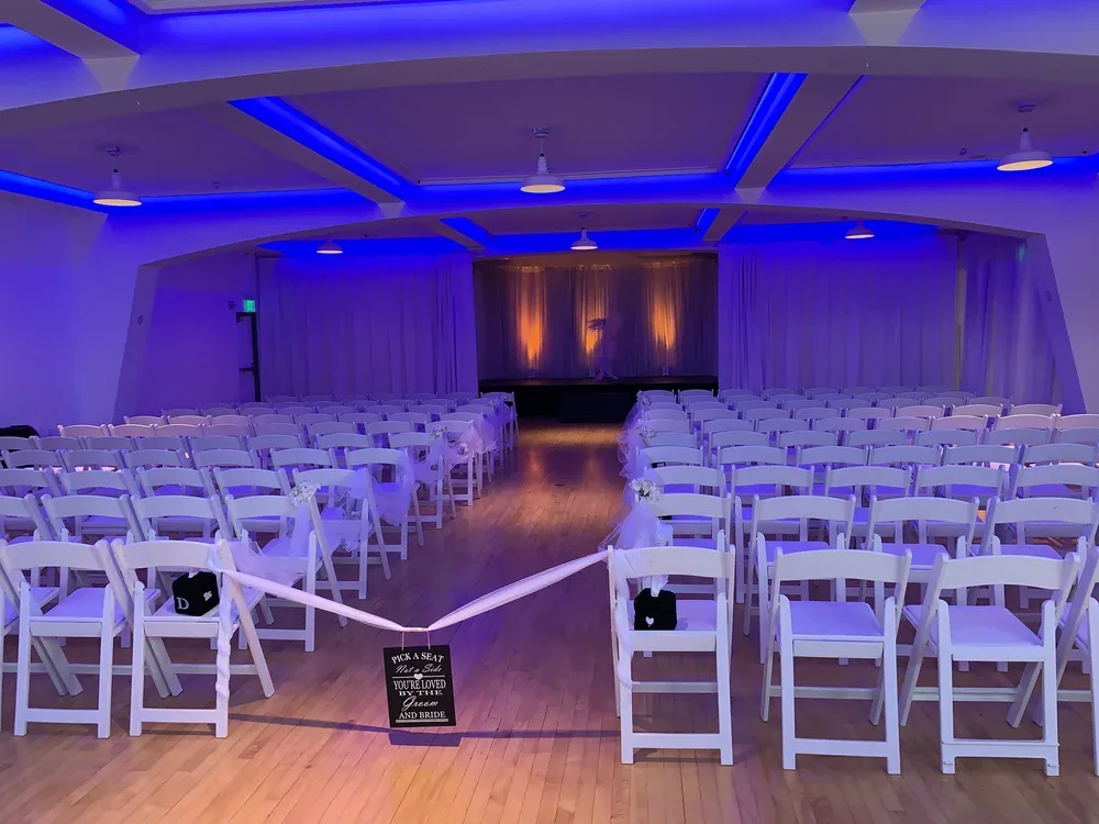 Wedding ceremony setup with white chairs and blue-lit stage in elegant event venue