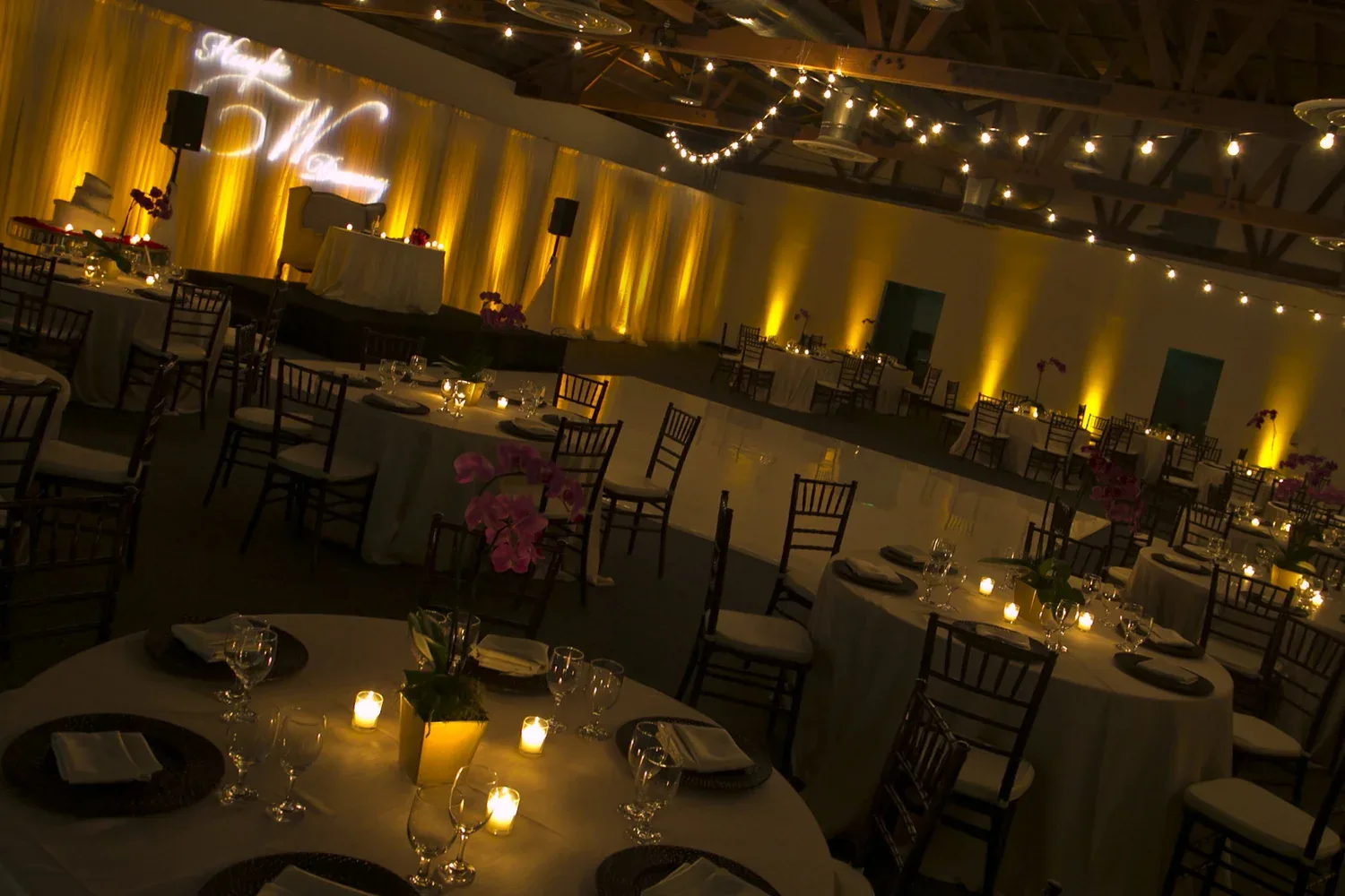 Elegant wedding reception setup with decorated tables and warm ambient lighting in event space