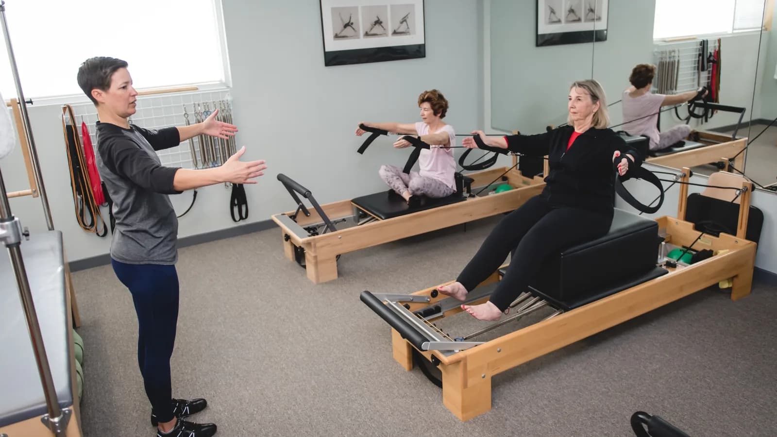 Pilates instructor teaching clients on reformer machines during a fitness class