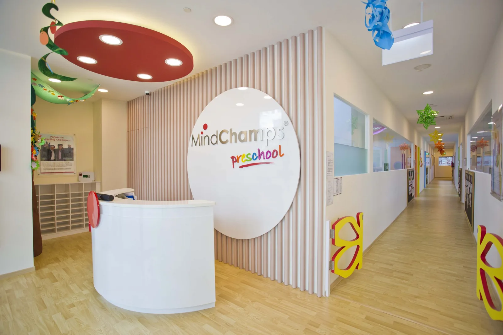 Modern preschool reception area with white desk, colorful ceiling, and bright hallway