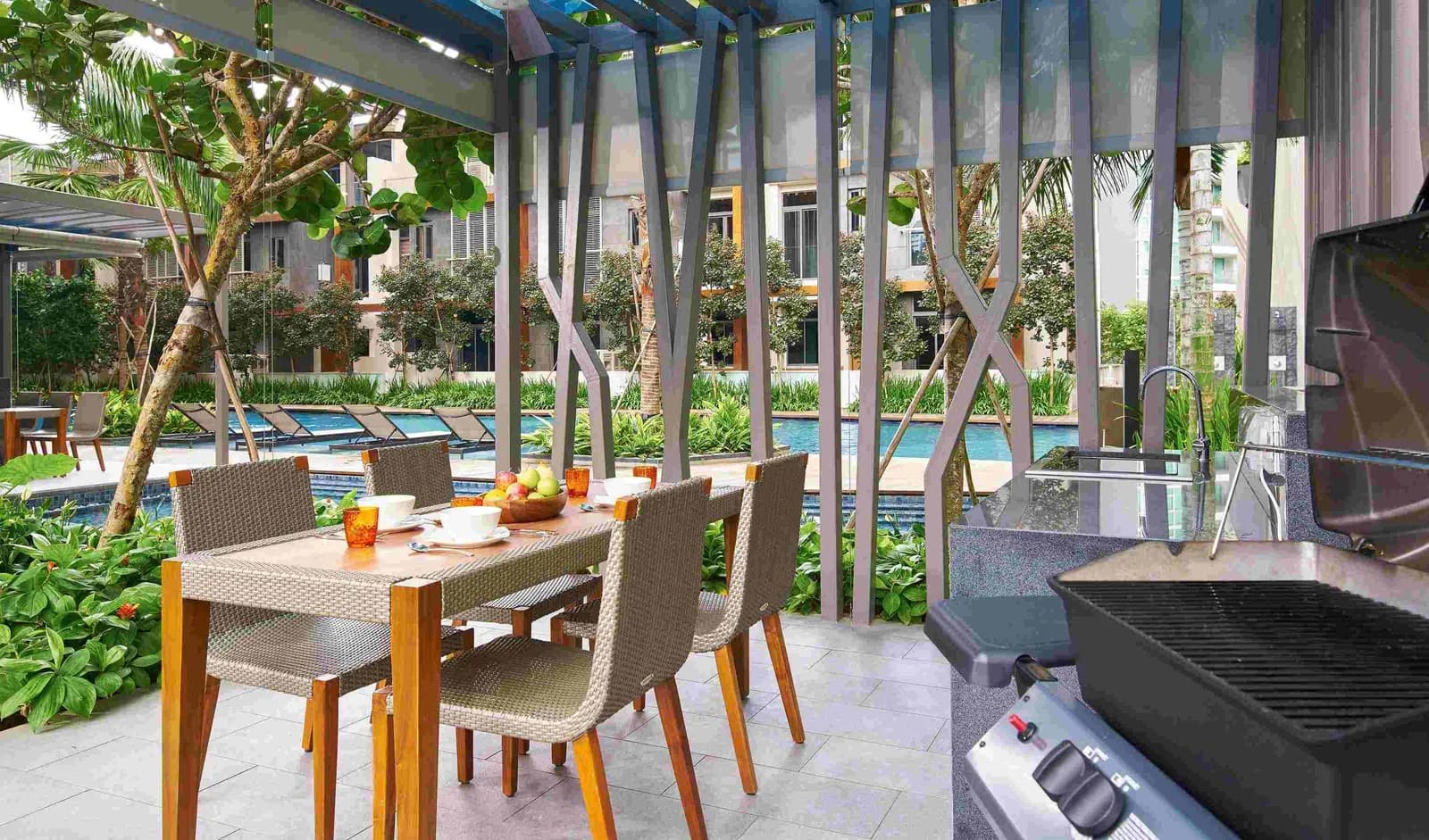 Outdoor terrace with dining table, grill, and pool view surrounded by tropical plants