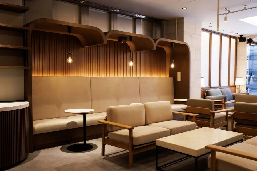 Modern hotel lounge with curved wooden design, cream seating, and pendant lights