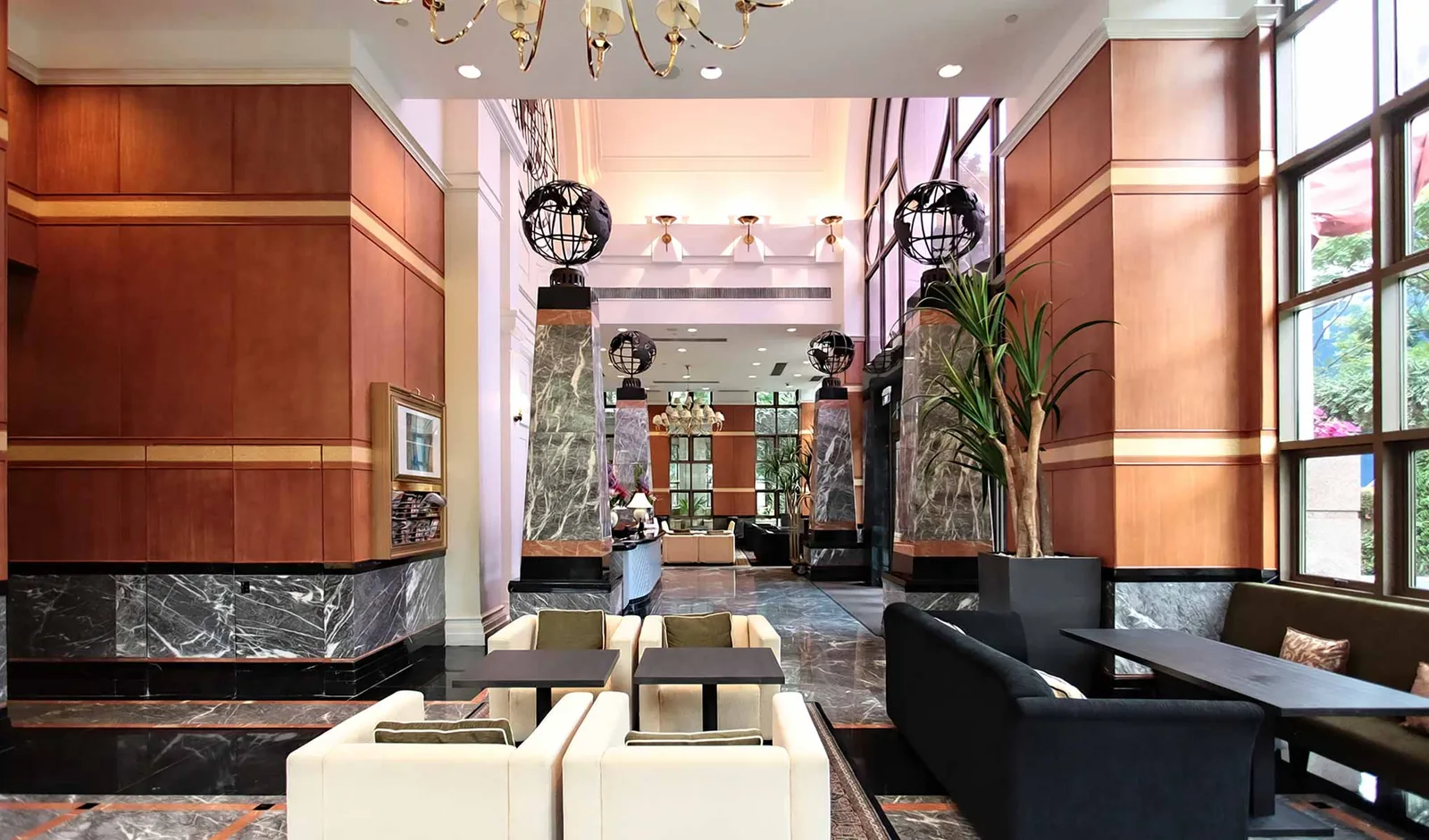 Hotel lobby with terracotta walls, marble features, black pendant lights, and modern seating area