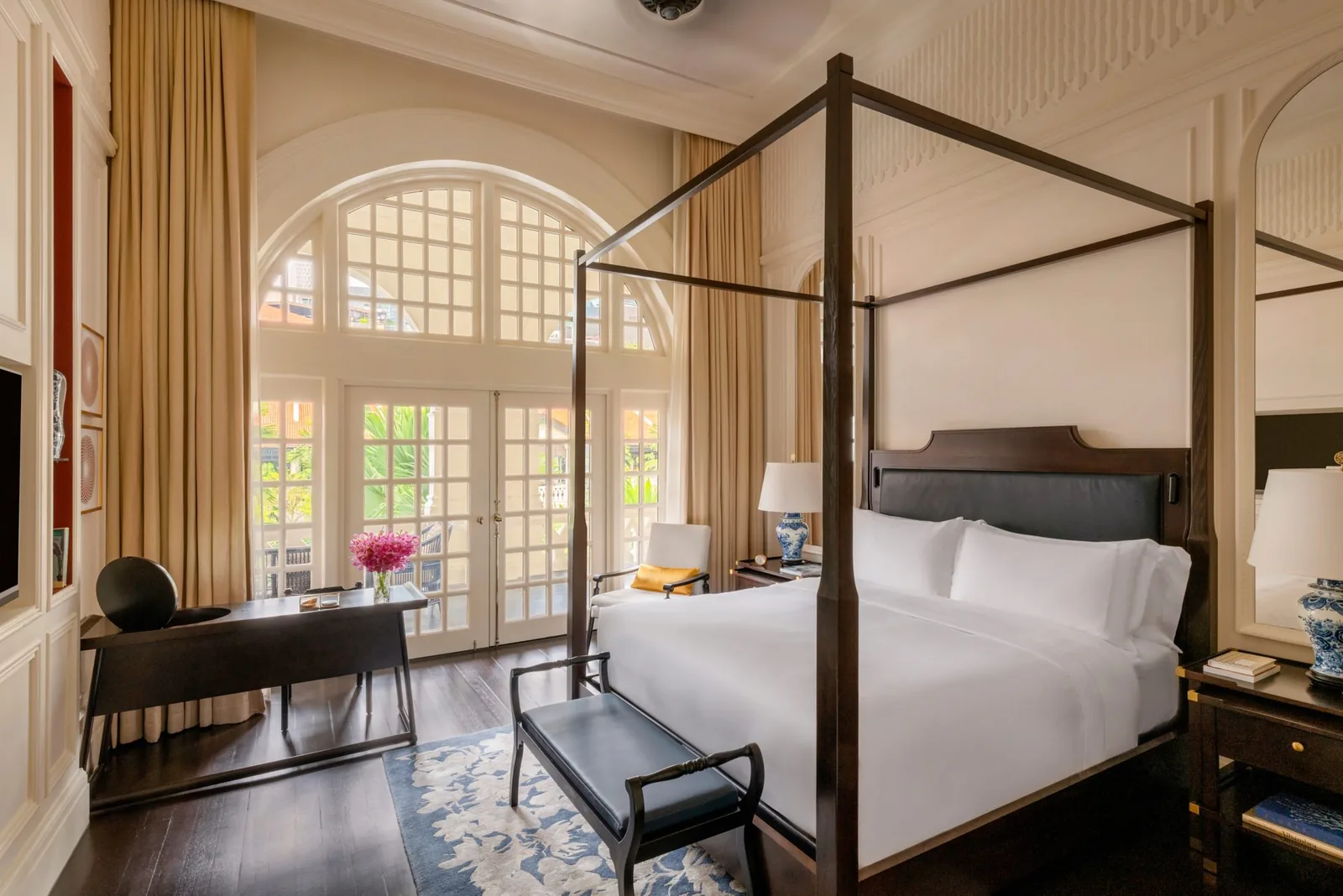 Elegant hotel suite with four-poster bed, arched windows, and classic furnishings