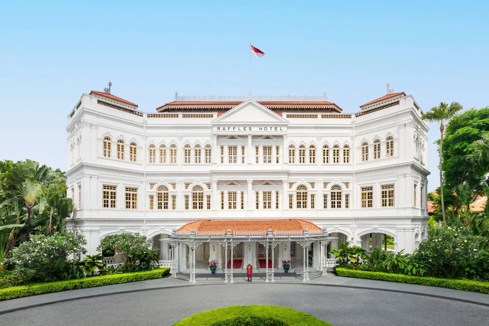 Raffles Singapore hotel's grand white colonial building with red-tiled roofs and manicured gardens.