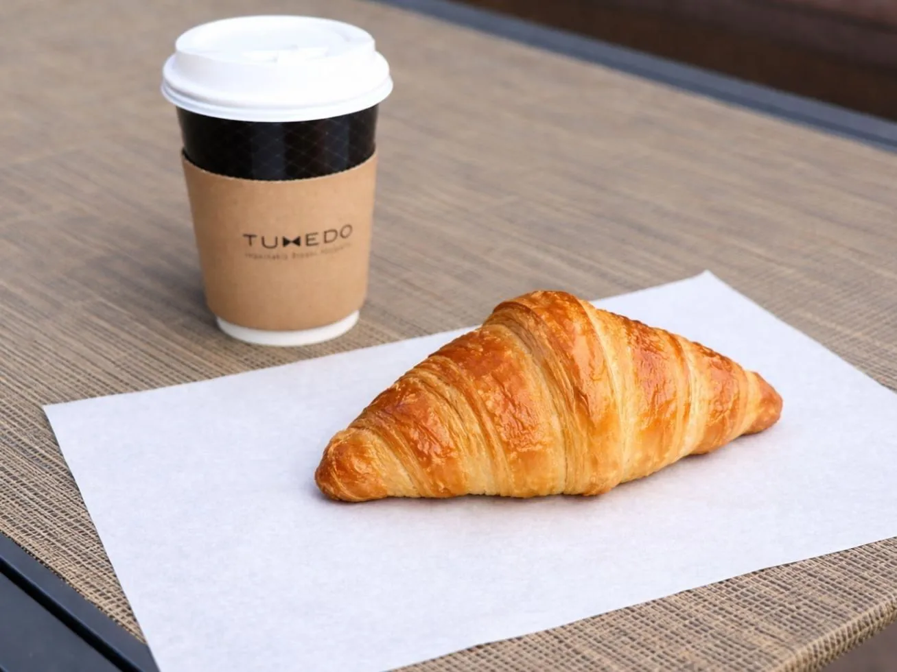 Golden croissant and branded coffee cup on a table
