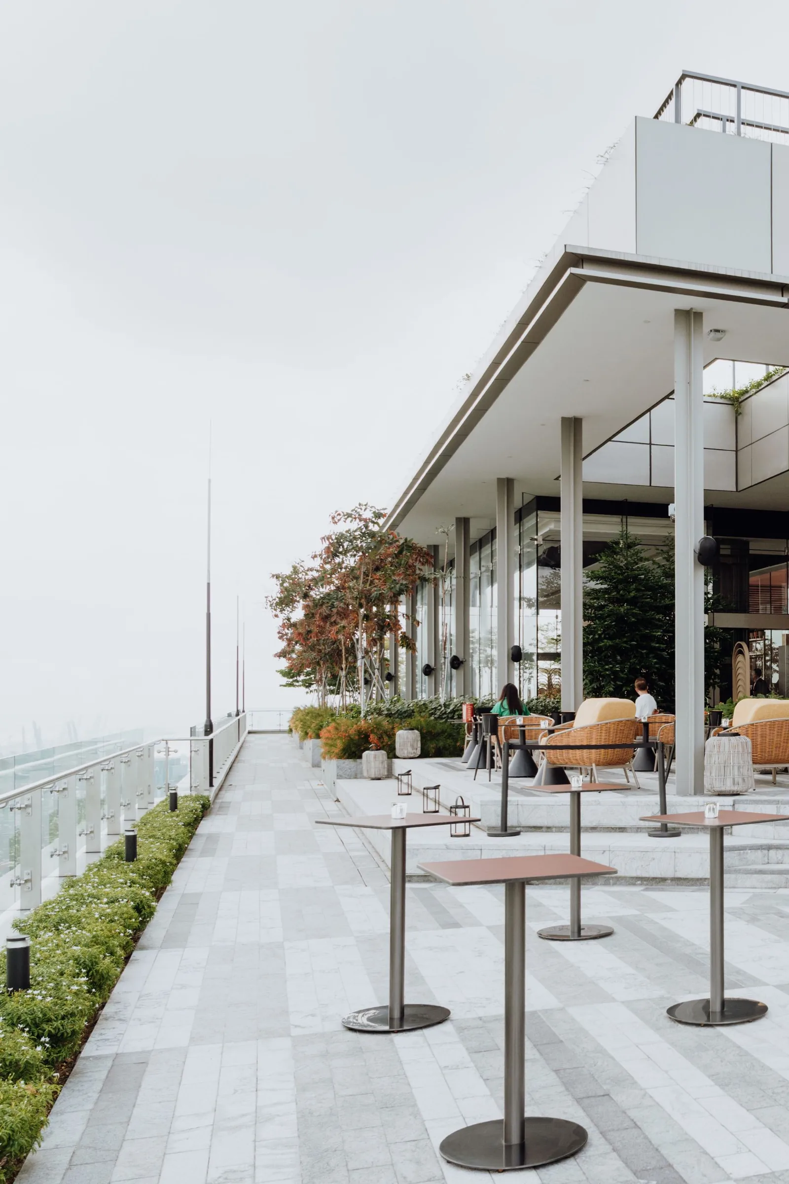 Modern rooftop terrace with dining areas, large windows, and waterfront views at an upscale venue