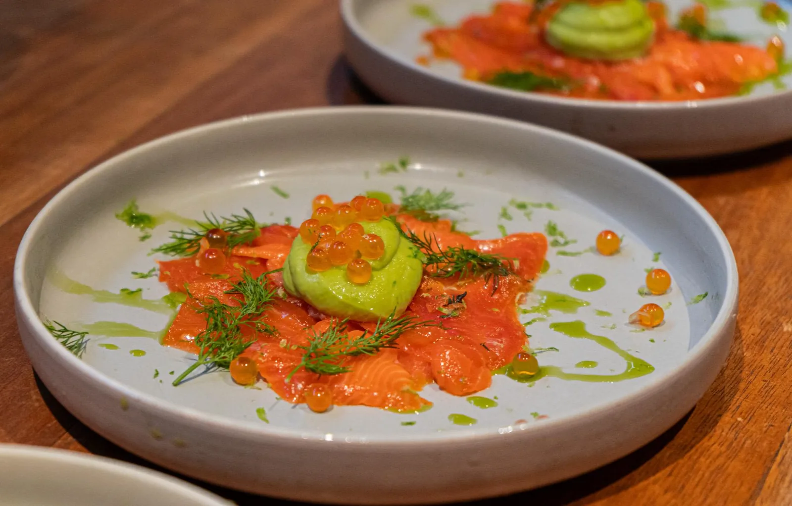 Plated salmon with avocado, caviar, and dill on white dish