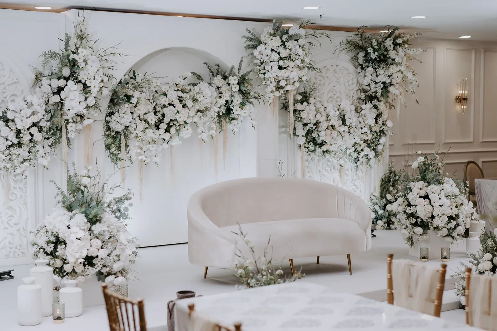Luxurious wedding venue with white flowers, curved sofa, and elegant decorations