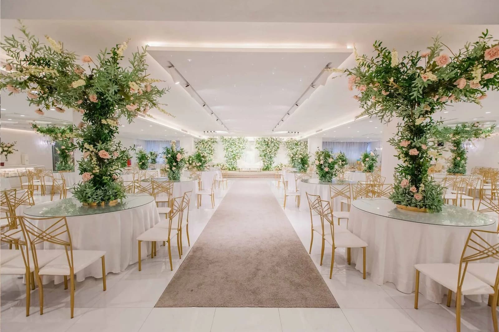 Wedding venue with round tables, gold chairs, and abundant floral decorations lining the space