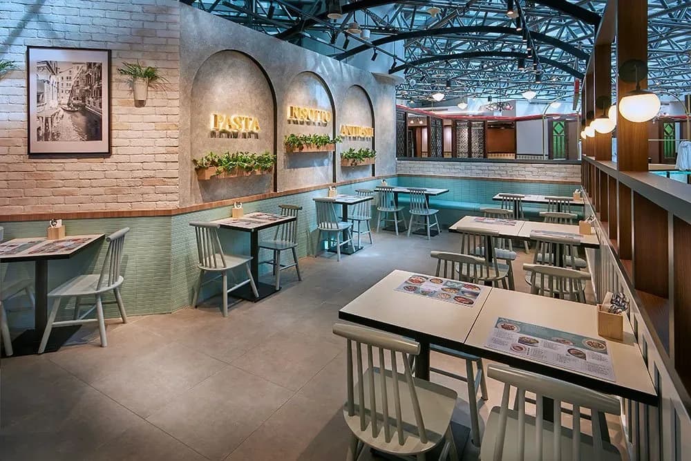 Modern Italian restaurant interior with dining tables, chairs, and illuminated pasta-themed wall alcoves