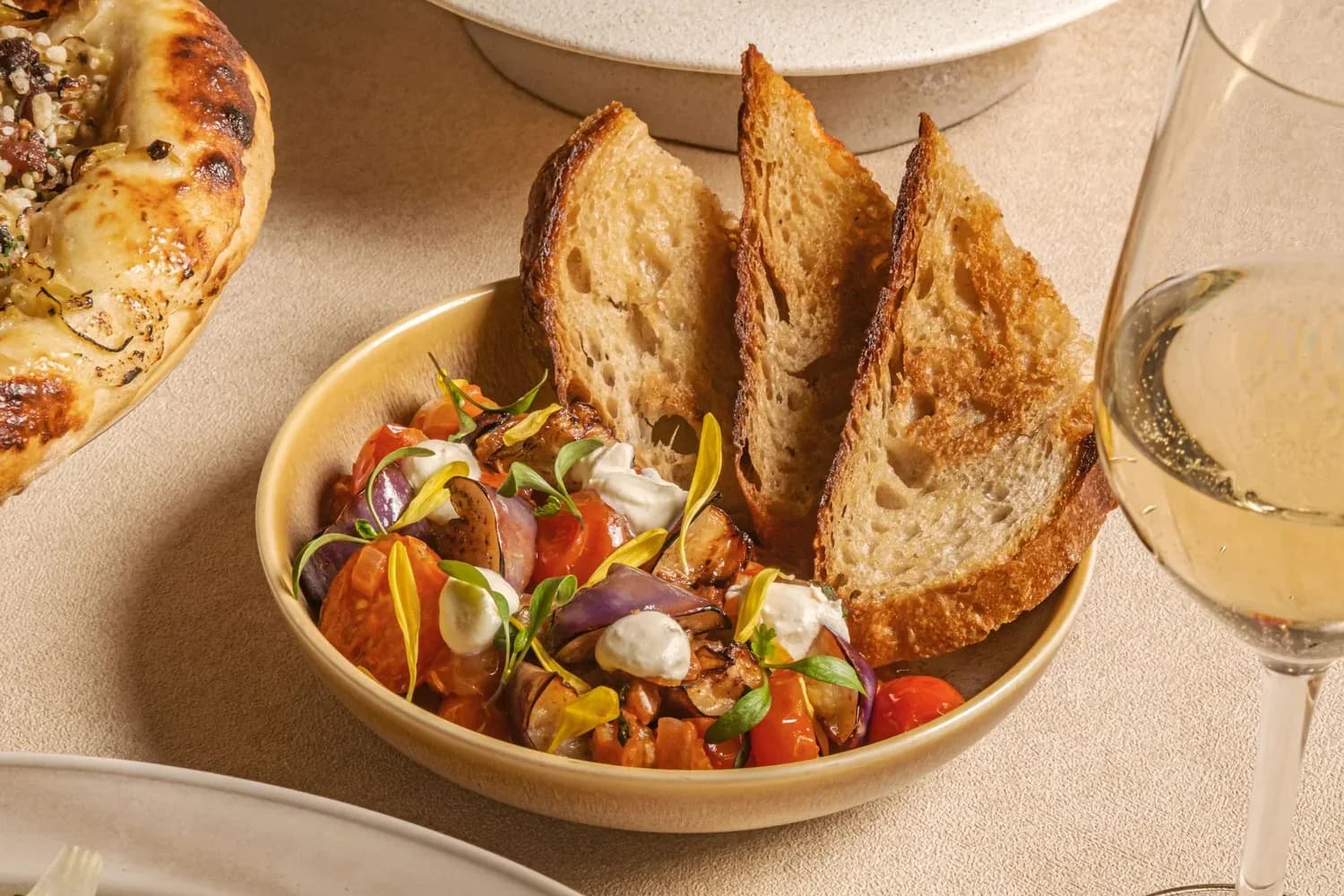 Toasted bread slices with a vibrant vegetable and cheese salad on a cream-colored plate