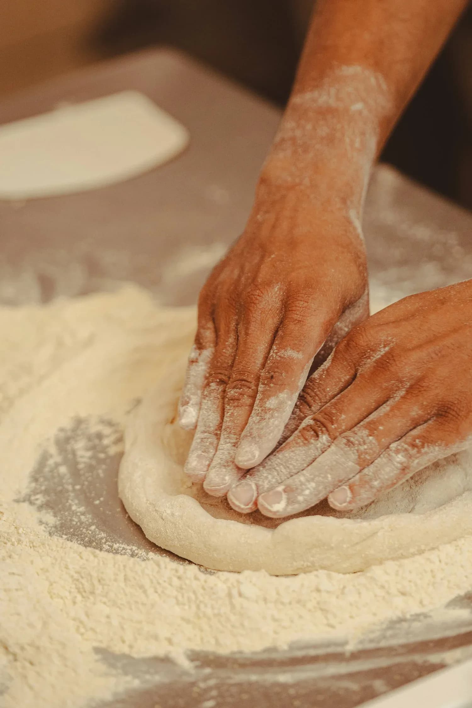 Baker's hands kneading fresh dough on a floured work surface