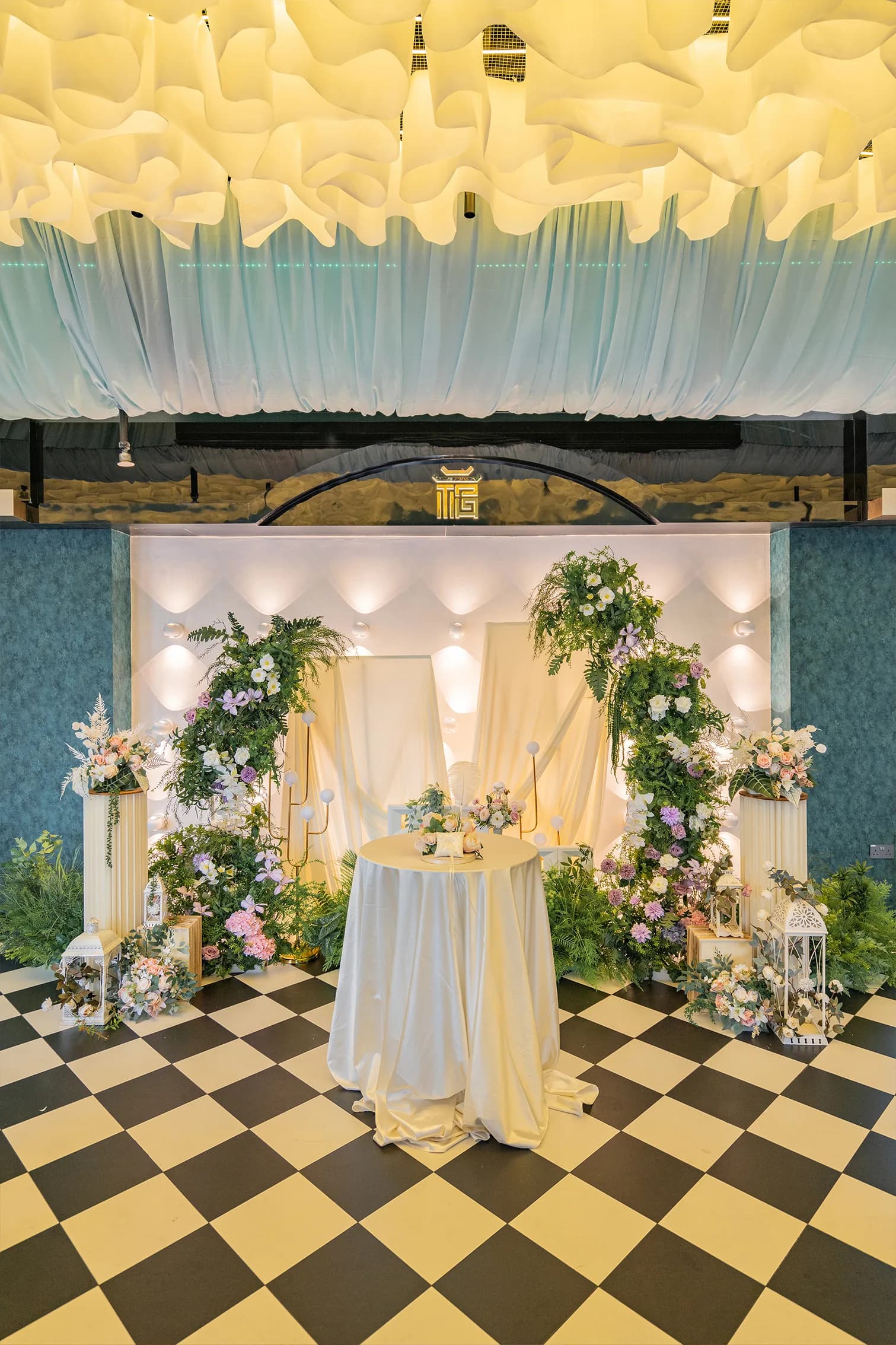 Wedding venue setup with floral arch installations, round table, and elegant lighting