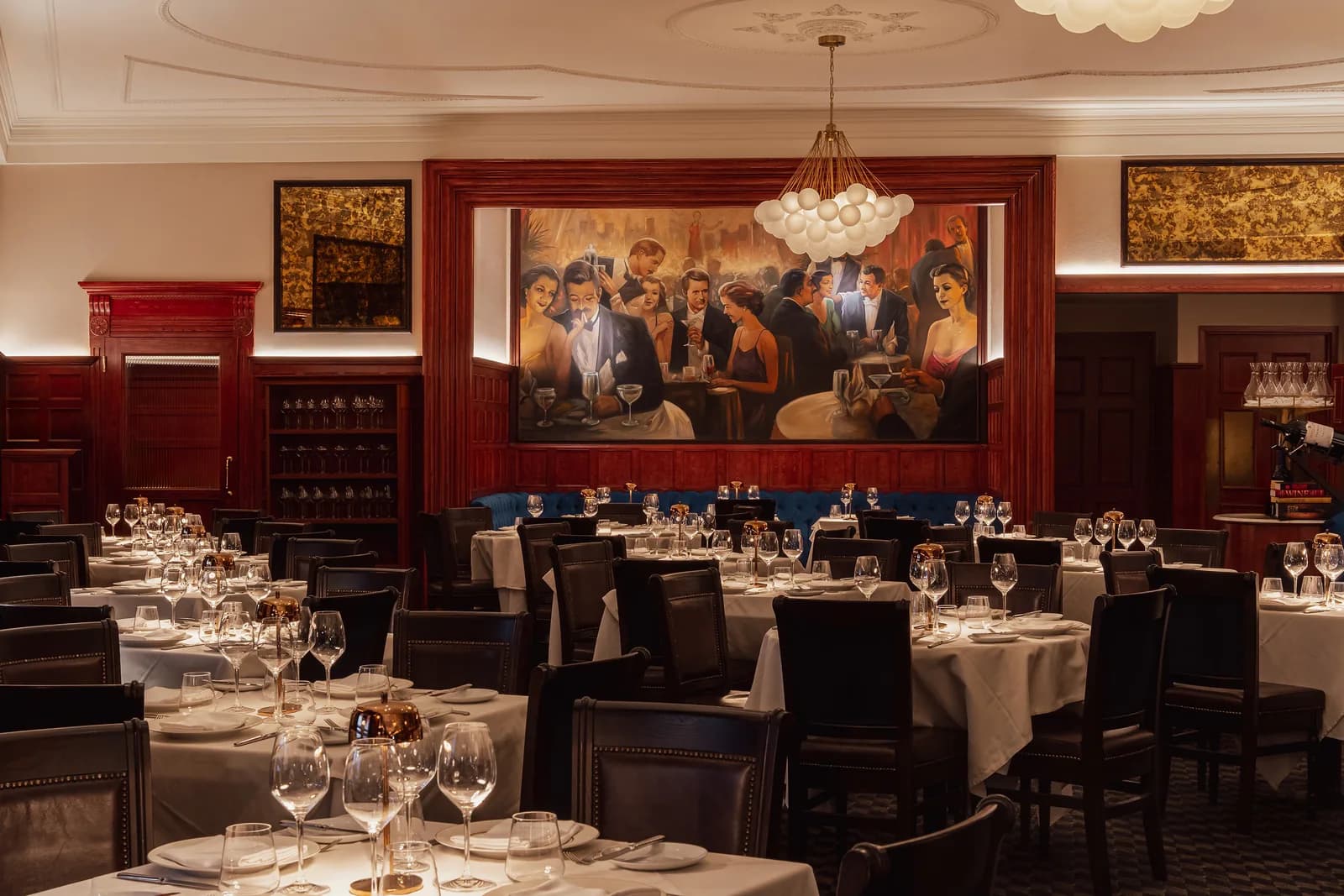 Fine dining restaurant with set tables, dark chairs, and elegant art deco-inspired décor
