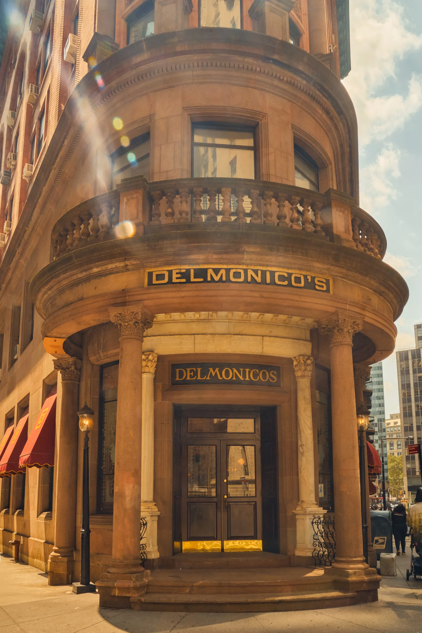 Delmonico's historic corner building with curved sandstone facade, columns, and ornate balcony