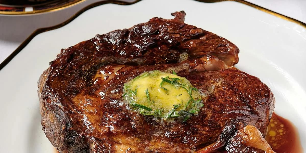 Seared steak with herb butter and scallion garnish on white plate
