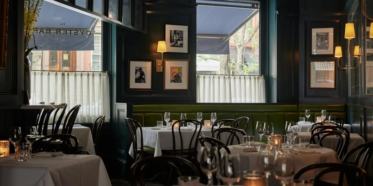 Upscale restaurant dining room with dark walls, white tables, and warm ambient lighting