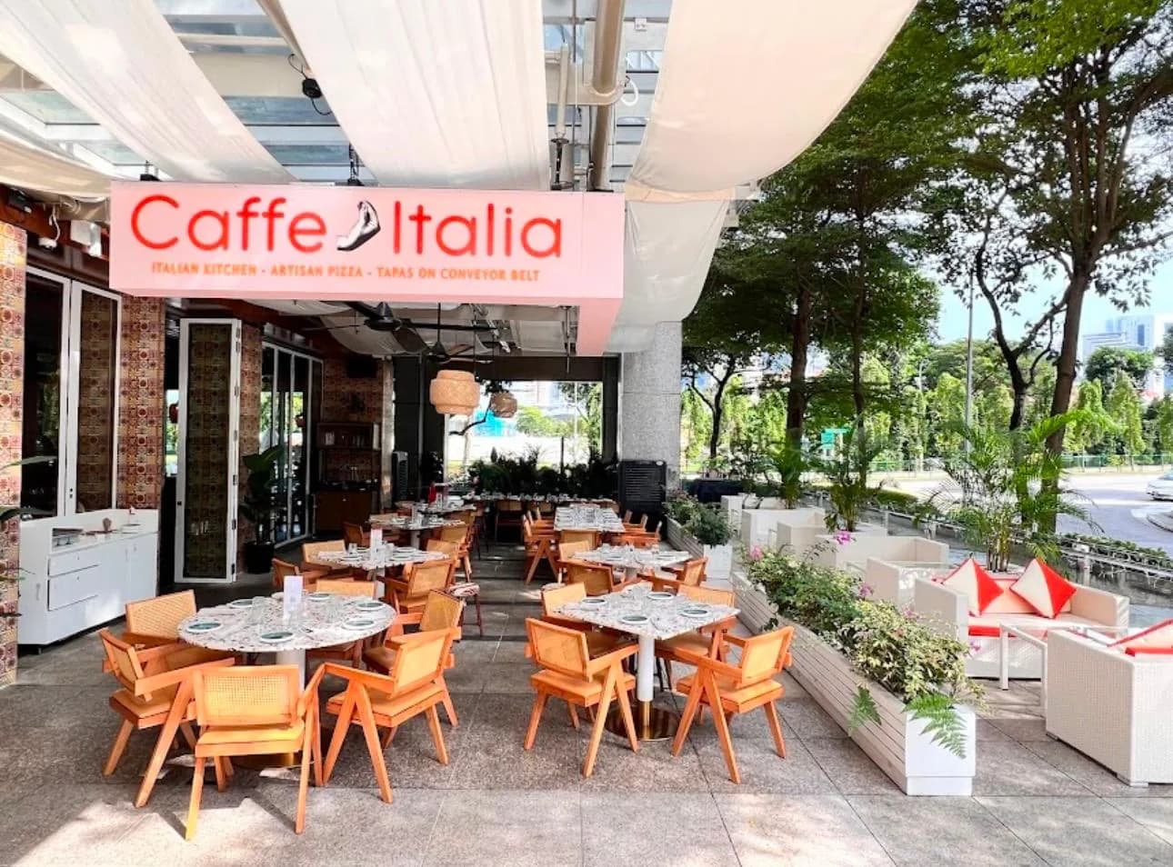 Caffe Italia outdoor terrace with wooden chairs, marble tables, and cream-colored shade canopy