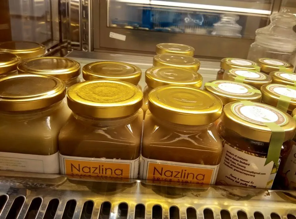 Shelves displaying Nazlina branded jars with golden lids containing spice products