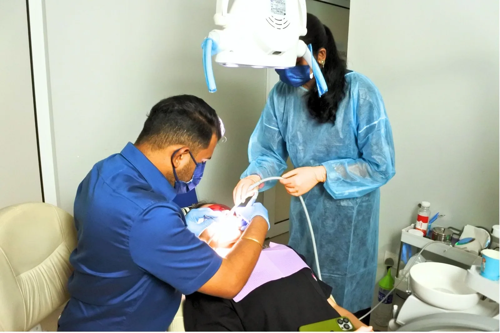 Dentist and assistant performing dental work on patient in treatment room