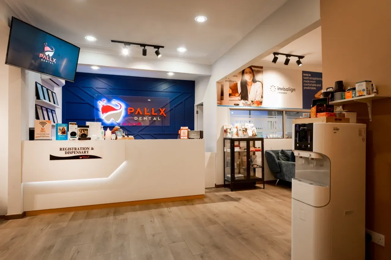 Modern dental clinic reception area with white desk, blue logo backdrop, and professional lighting