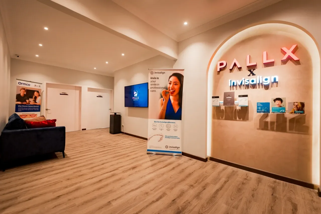 Dental clinic reception with neon signage, modern furnishings, and Invisalign product display