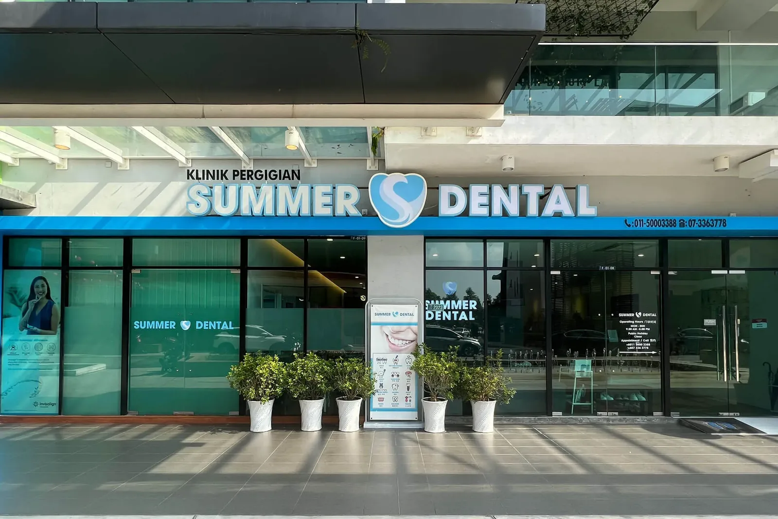 Summer Dental Clinic storefront with blue signage, glass windows, and potted plants