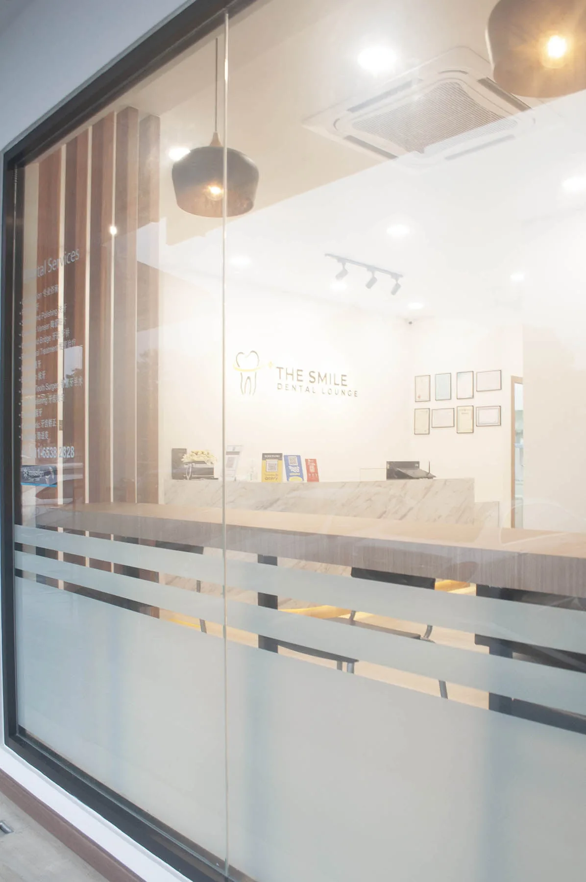 Modern dental clinic reception area with white interior, wooden slats, pendant lighting, and branded signage