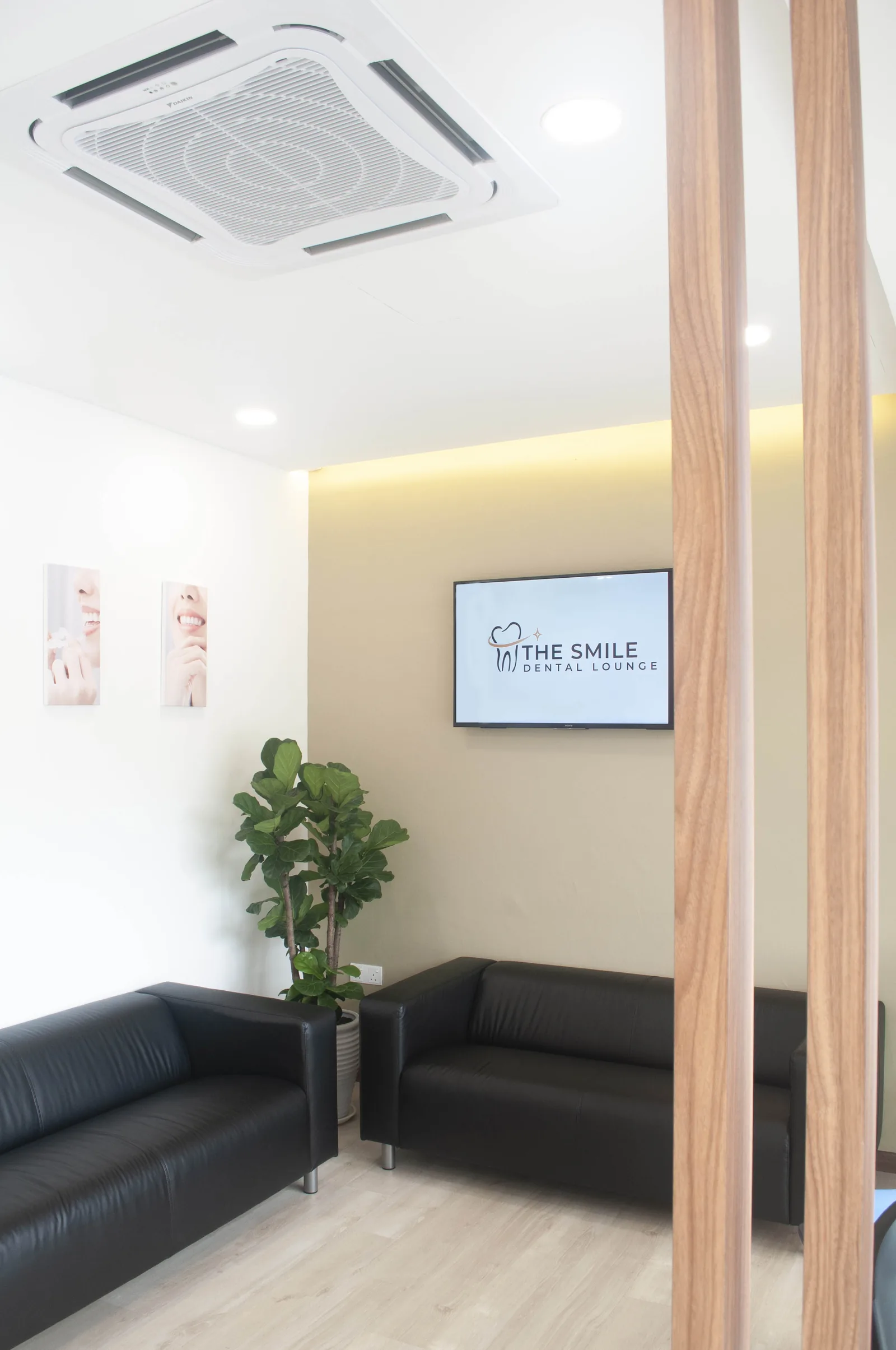 Modern dental clinic waiting room with black leather seating, wood partitions, and branded display screen