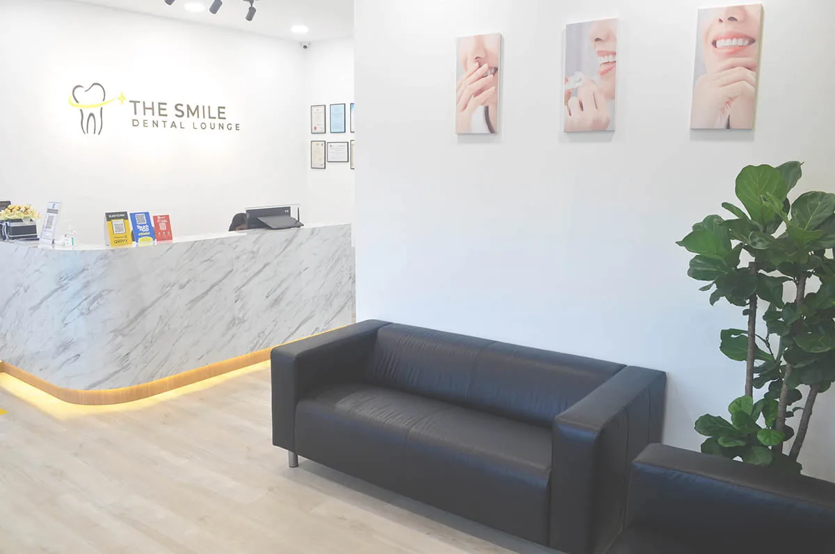 Dental clinic reception area with marble counter, black sofa, and treatment display panels on wall