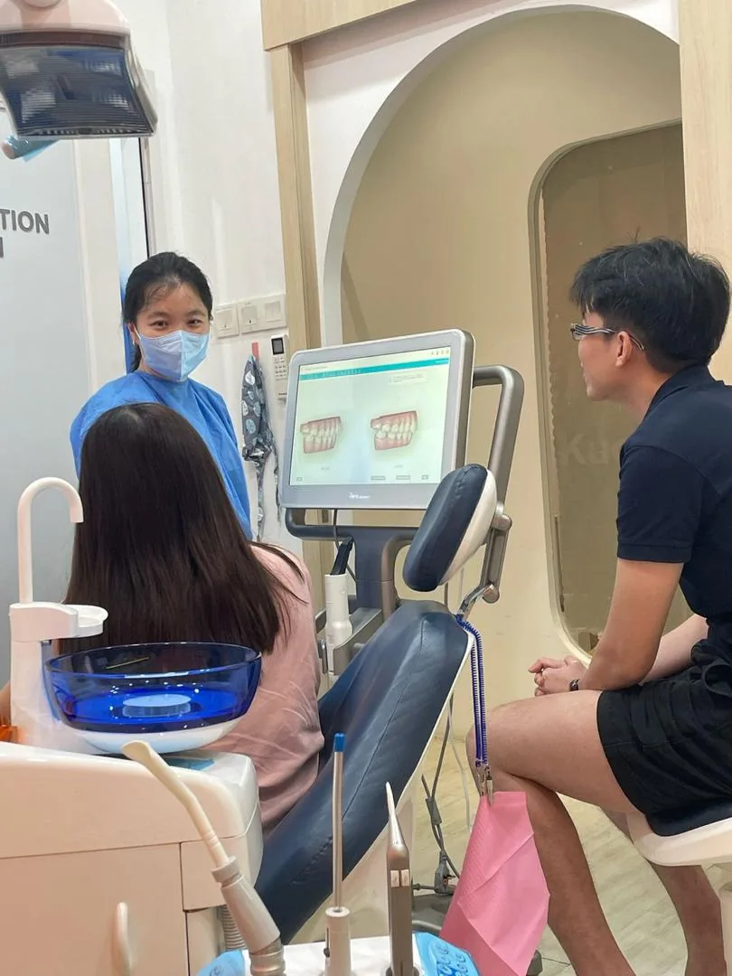 Dentist showing tooth scan images to patient at chair-side monitor in modern dental clinic
