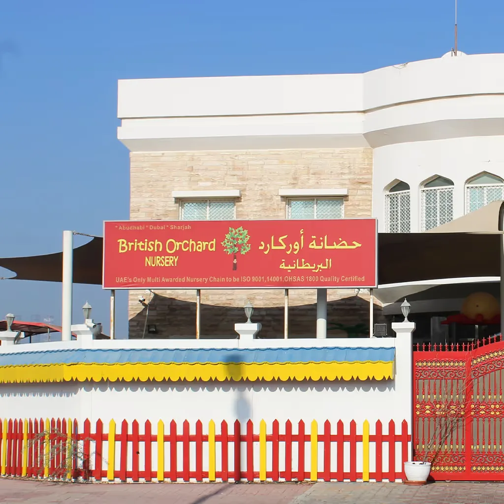 British Orchard Nursery storefront with red sign, colorful picket fence, and white building entrance
