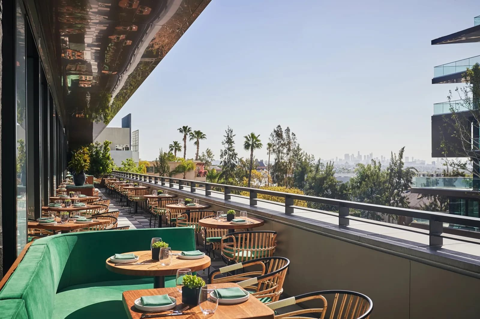 Rooftop restaurant terrace with dining tables, woven chairs, and city skyline views