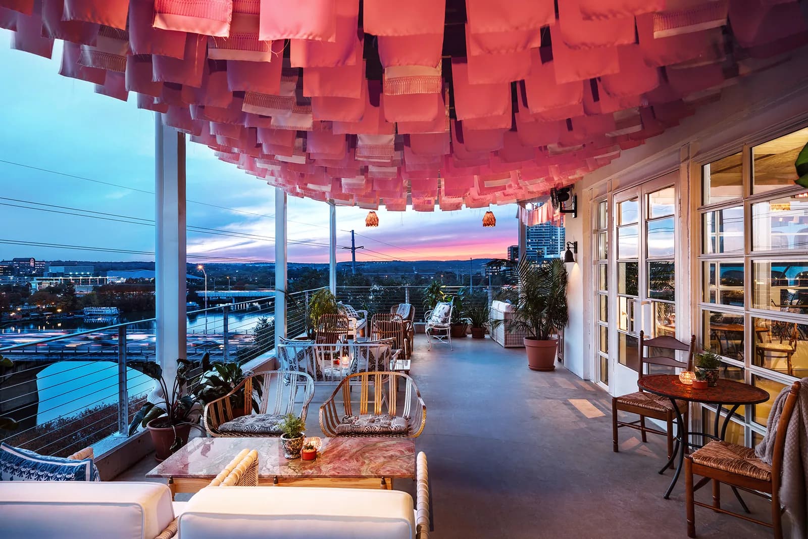 Rooftop terrace with red ceiling panels overlooking city at sunset, modern seating and panoramic views