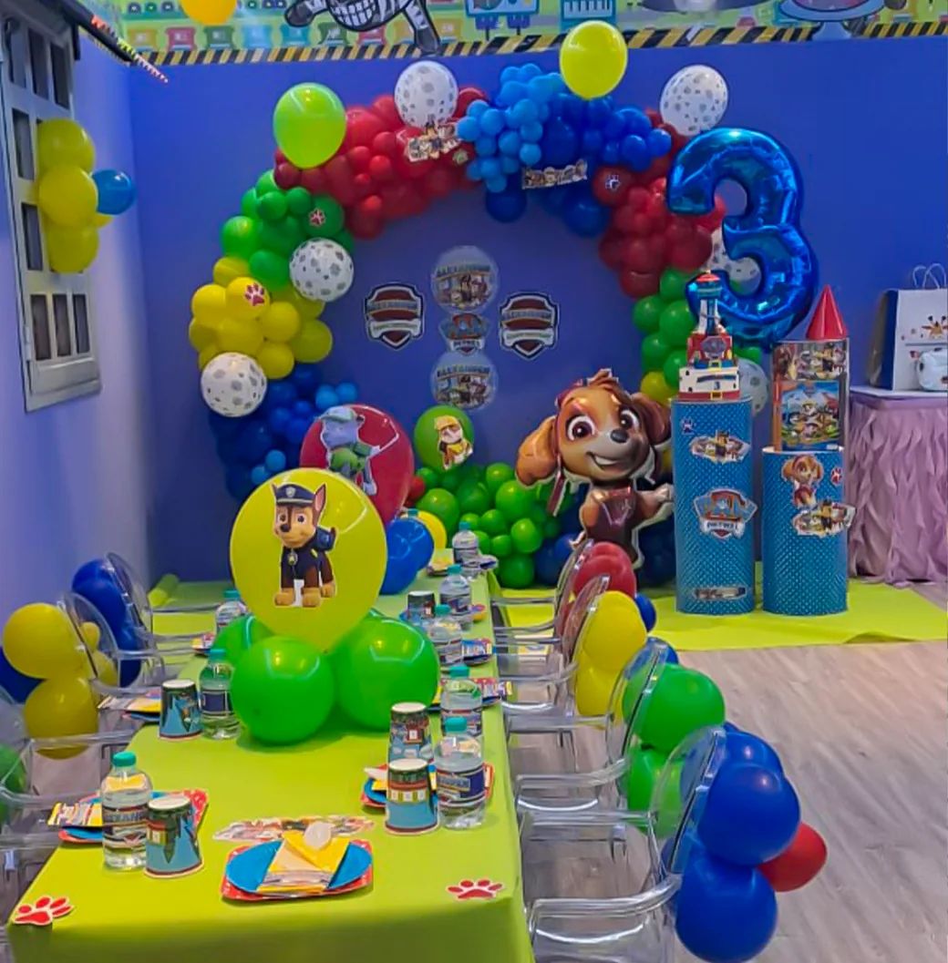 Paw Patrol themed party room with colorful balloon arch, decorated table, and character cutouts