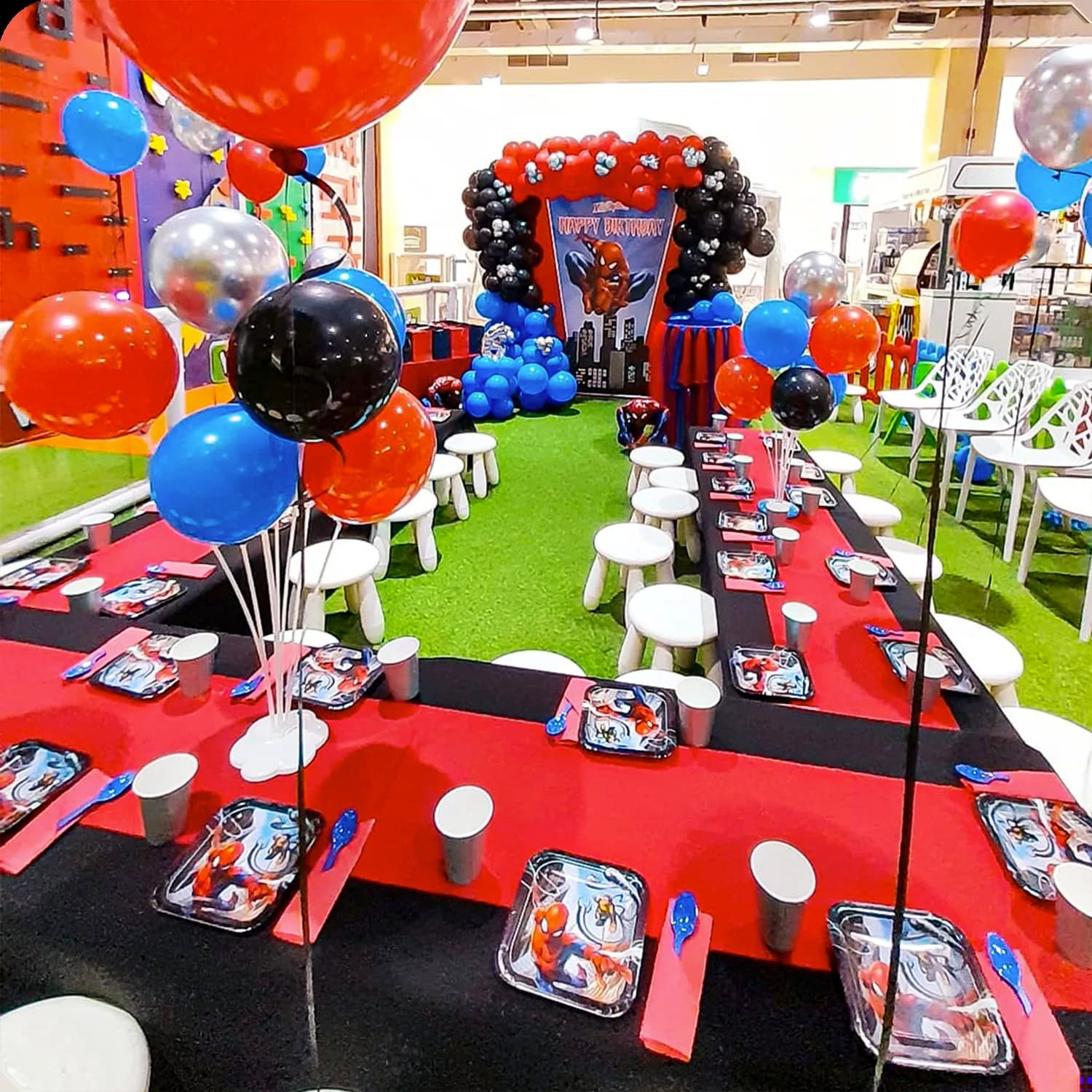 Birthday party room decorated with red tables, colorful balloons, and character-themed setup for children's celebration.