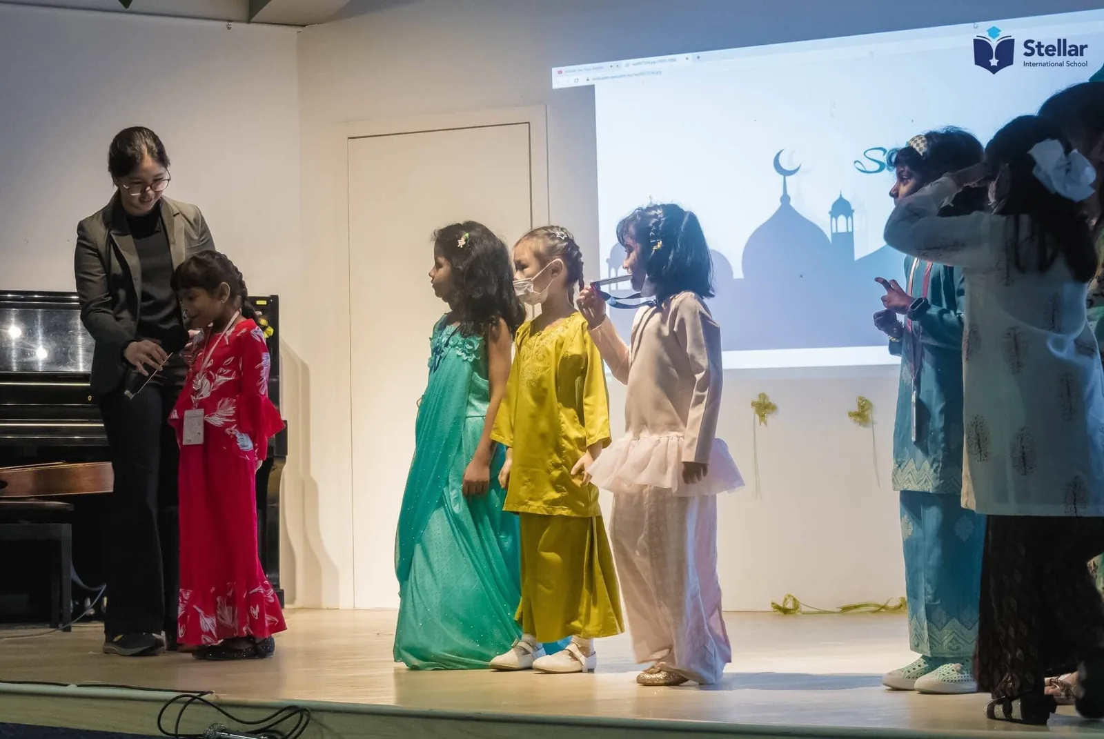Children in traditional dress performing on stage at Stellar Playschool cultural event