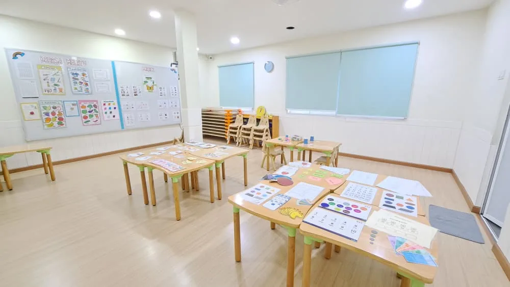 Preschool classroom with child-sized wooden furniture, learning materials on tables and walls