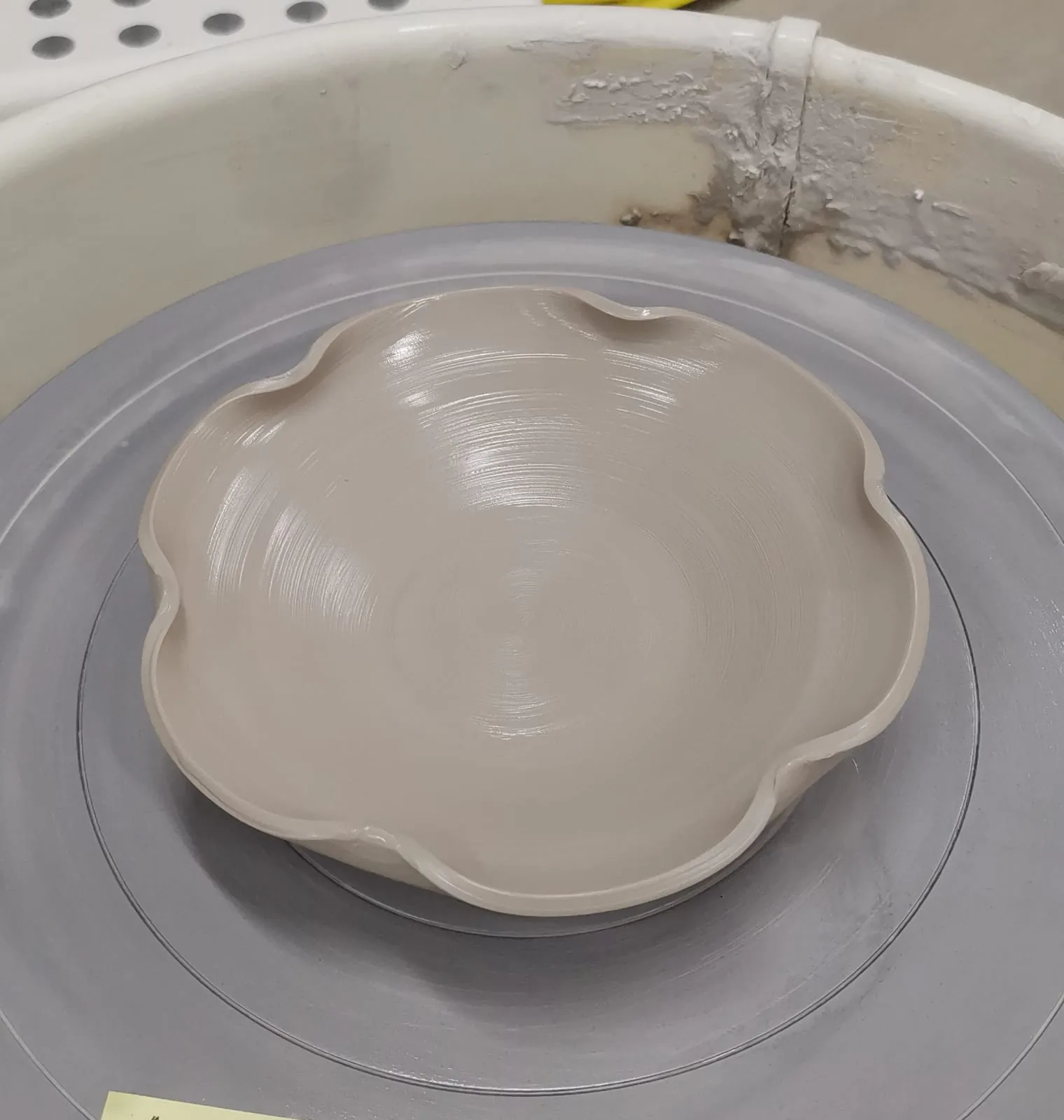 Handmade ceramic bowl with undulating edges on a pottery wheel