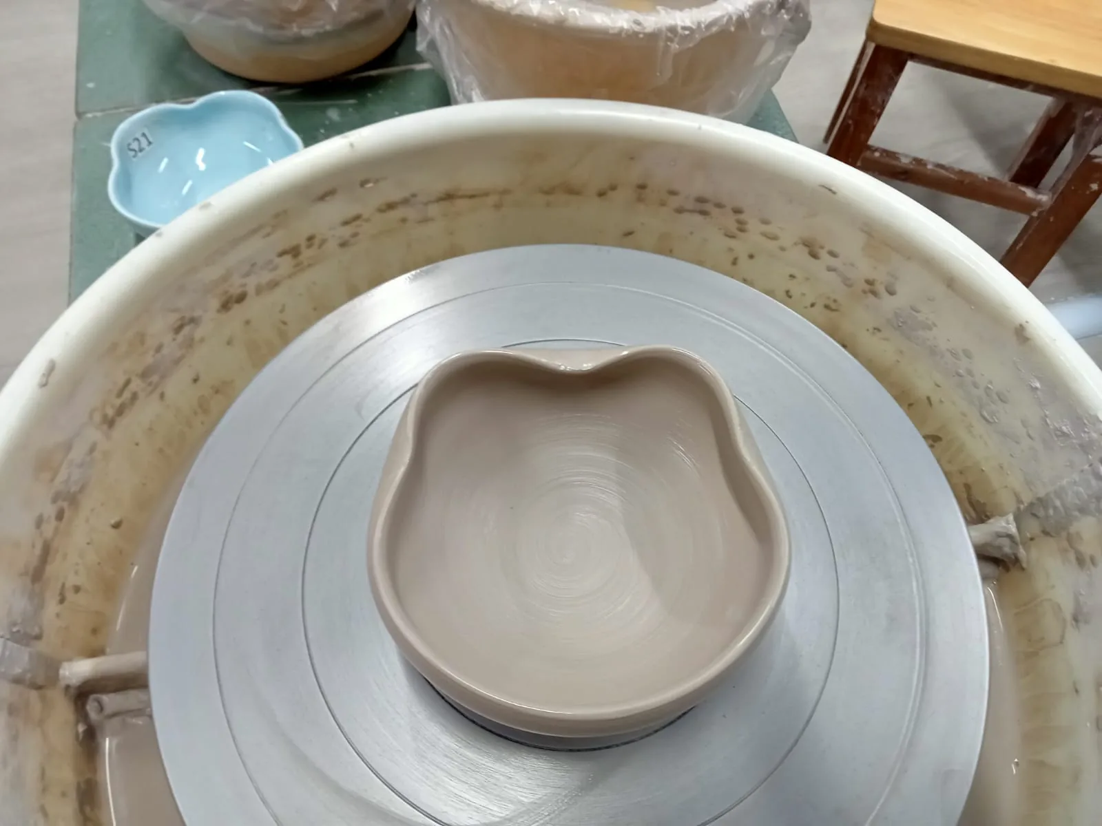 Clay bowl being formed on a pottery wheel at a pottery studio