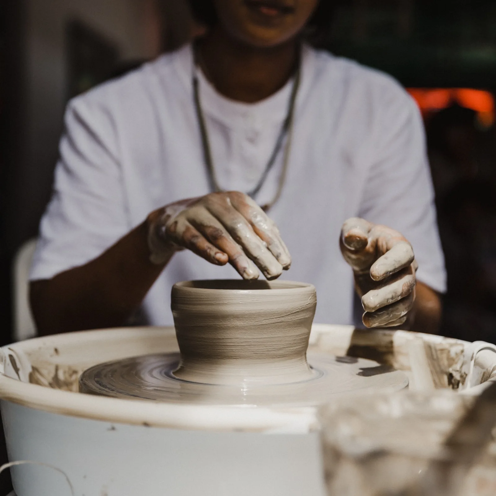 Potter's hands shaping clay on a spinning pottery wheel