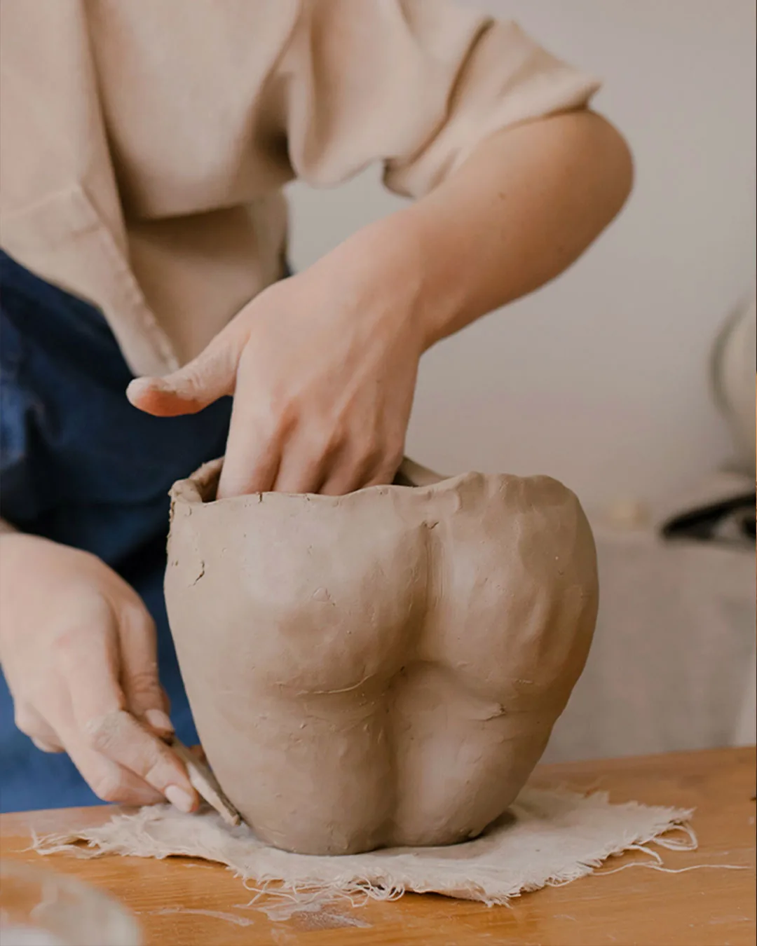 Potter's hands shaping a clay form during pottery work