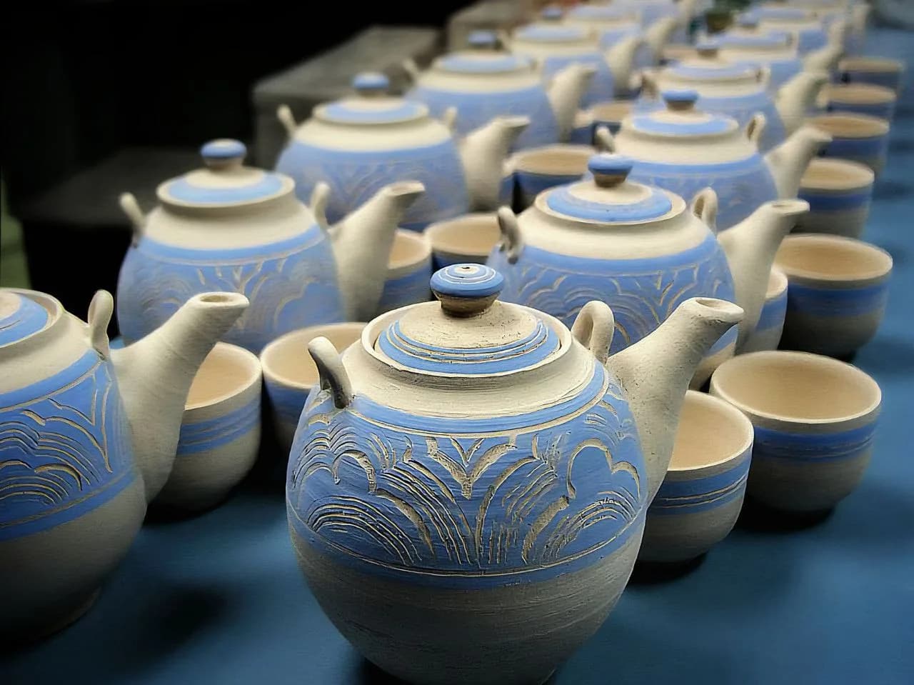 Rows of blue and cream ceramic teapots with ornamental designs displayed together