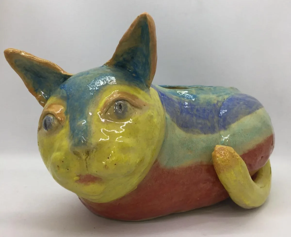 Colorful ceramic cat figurine with yellow face, gold ears, and blue-teal-rust glazed body.