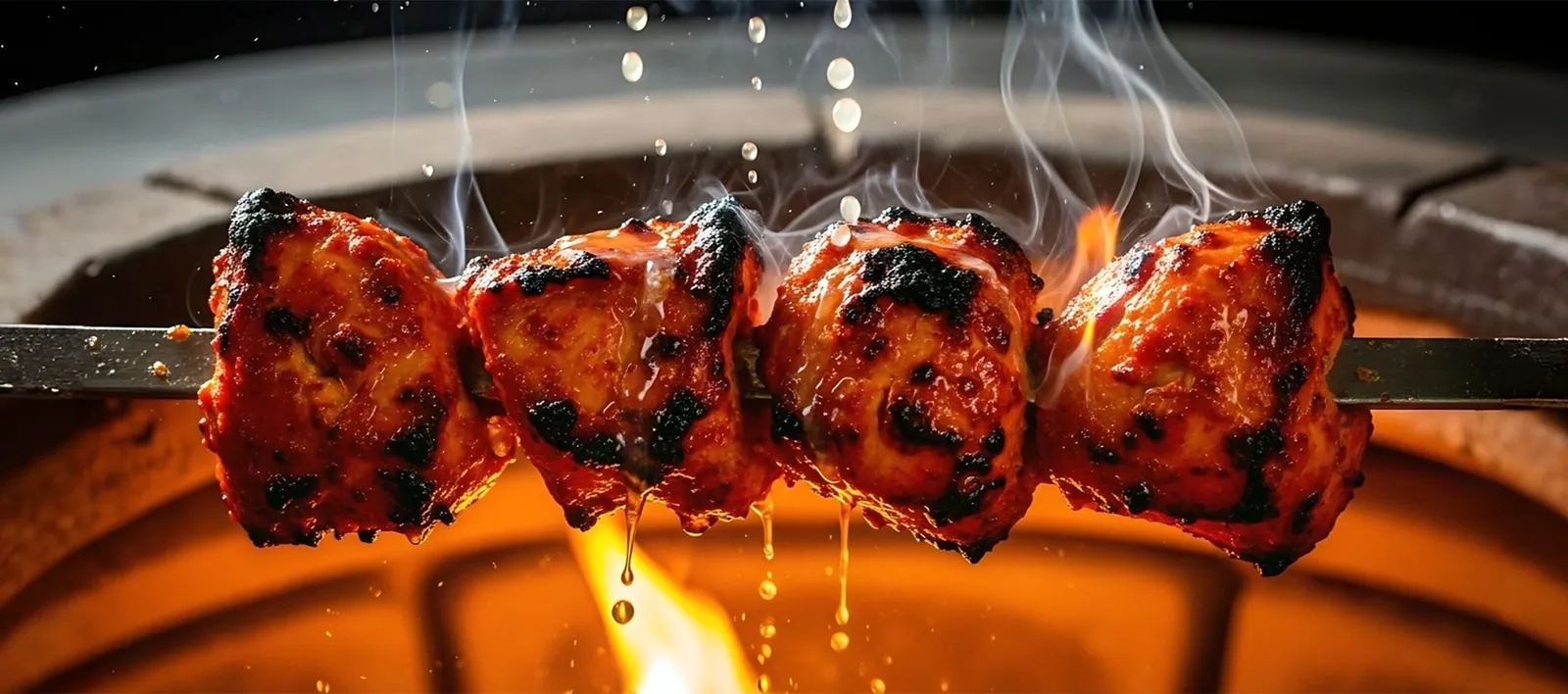 Tandoori meat kebabs on skewers over glowing coals with flames and dripping juices.