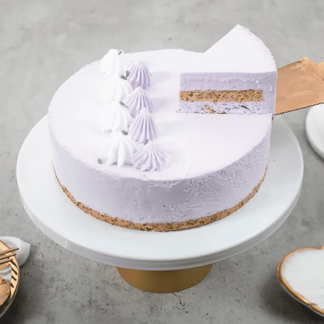 Lavender frosted layer cake with meringue peaks and cross-section view on white plate