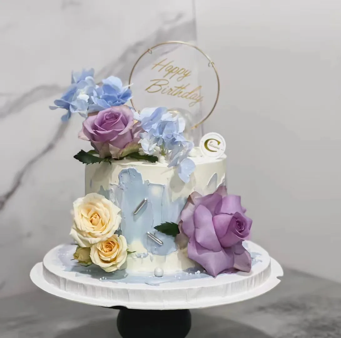 Two-tier birthday cake with fresh flowers and blue watercolor design